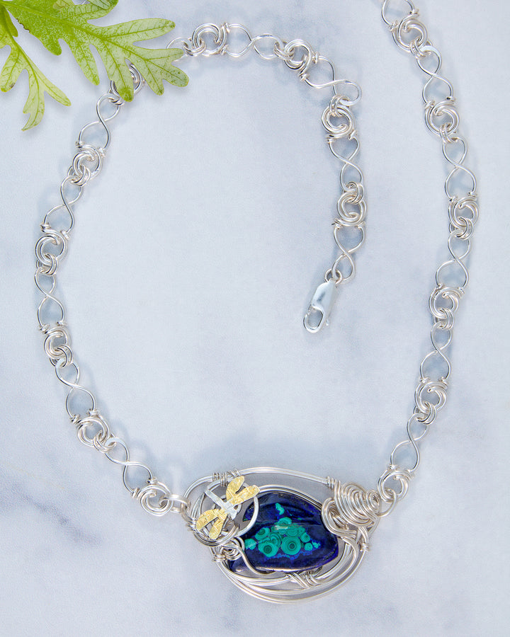 Silver chain necklace with a blue and green pendant on a light gray background