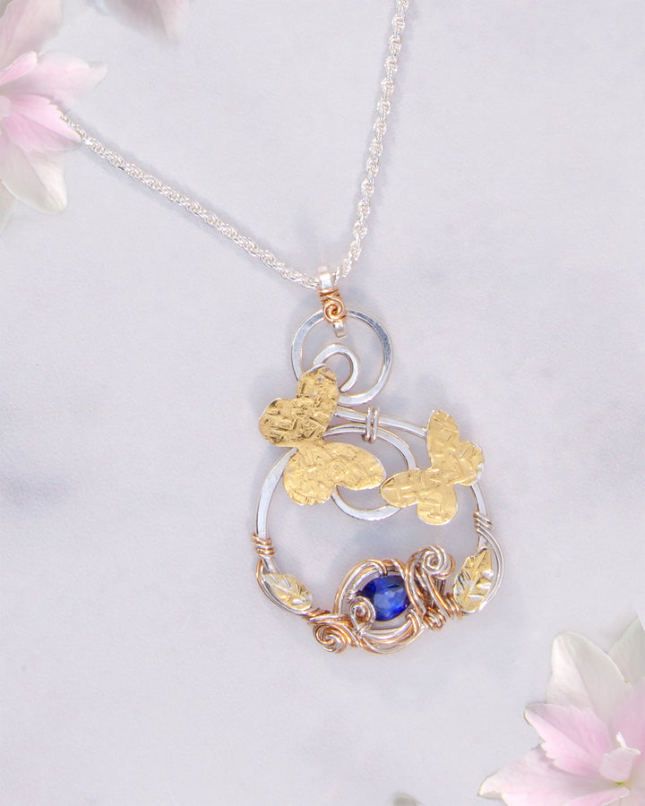 Necklace with a gold and silver butterfly pendant on a light background
