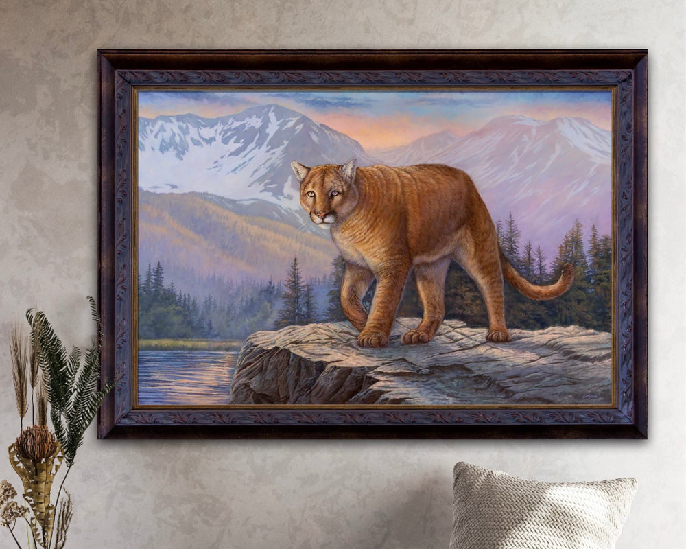 Framed painting of a mountain lion on a rock with mountains and trees in the background.