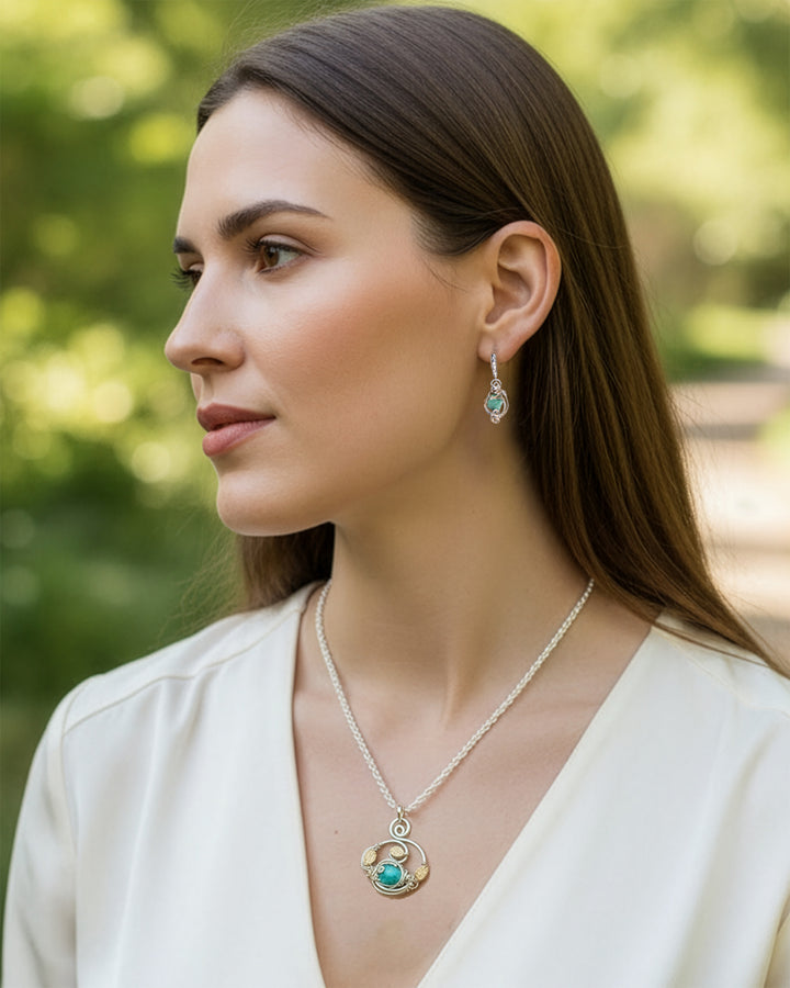 Woman wearing a necklace and earrings with a blurred green background